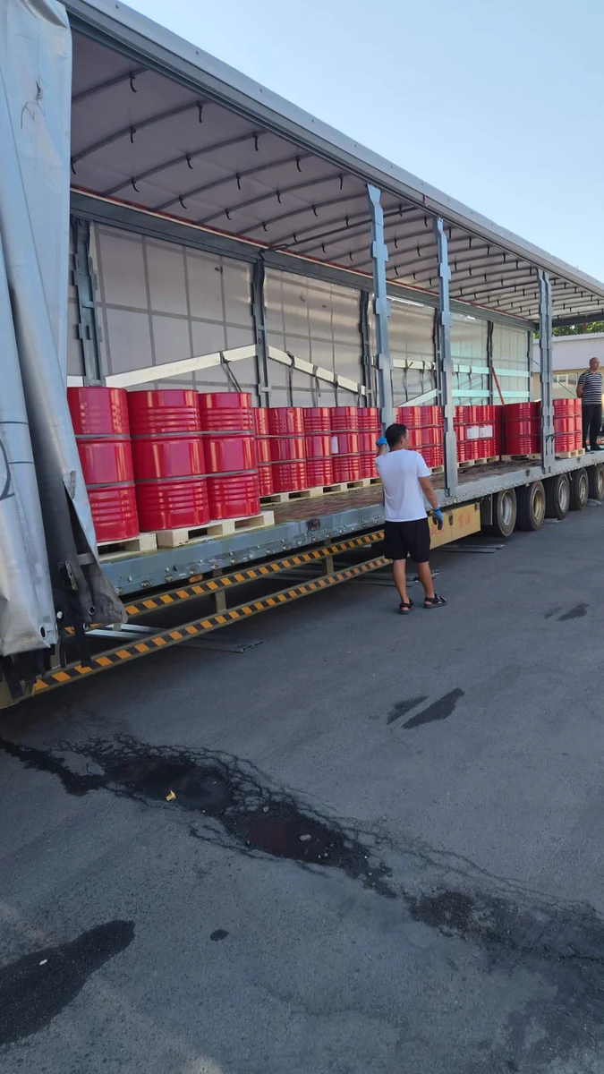 Красные бочки на паллетах вдоль борта грузового полуприцепа